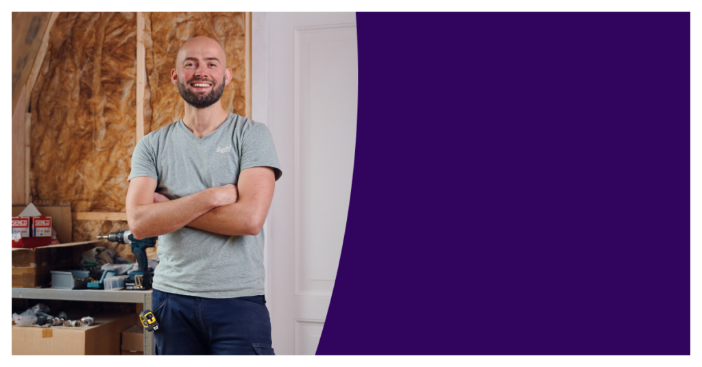 Jongere man die met zijn armen over elkaar staat en blij is in zijn klusruimte