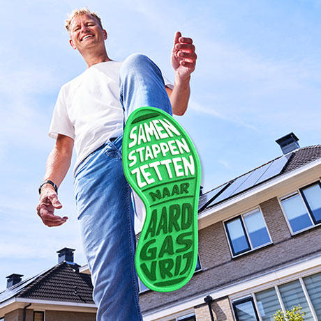 Grote, groene voetafdruk van een man, buiten, helder weer, met de tekst (op de voetafdruk): ''Samen stappen zetten naar Aardgasvrij''